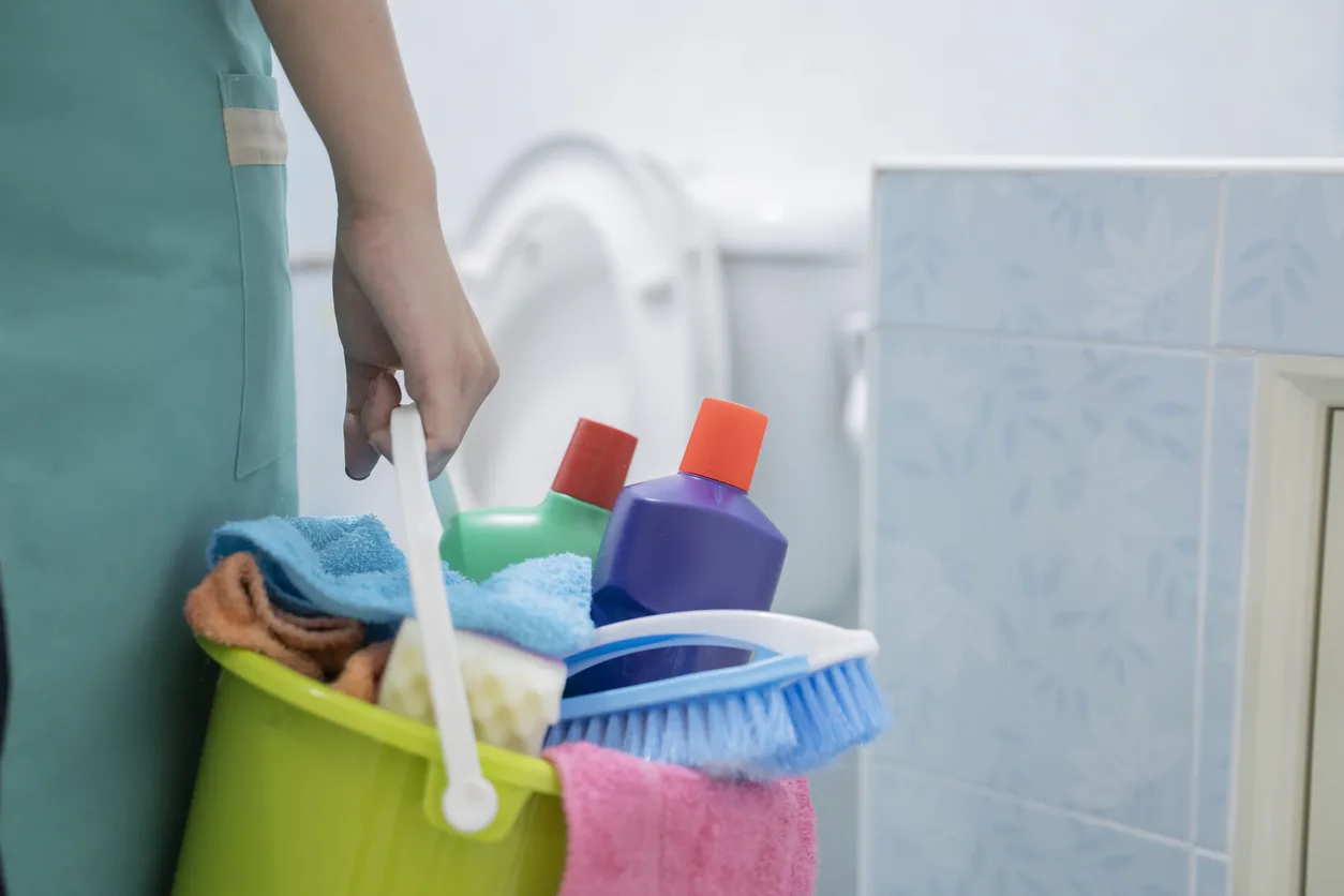 Woman with a bucket and cleaning products on blurred background. Image